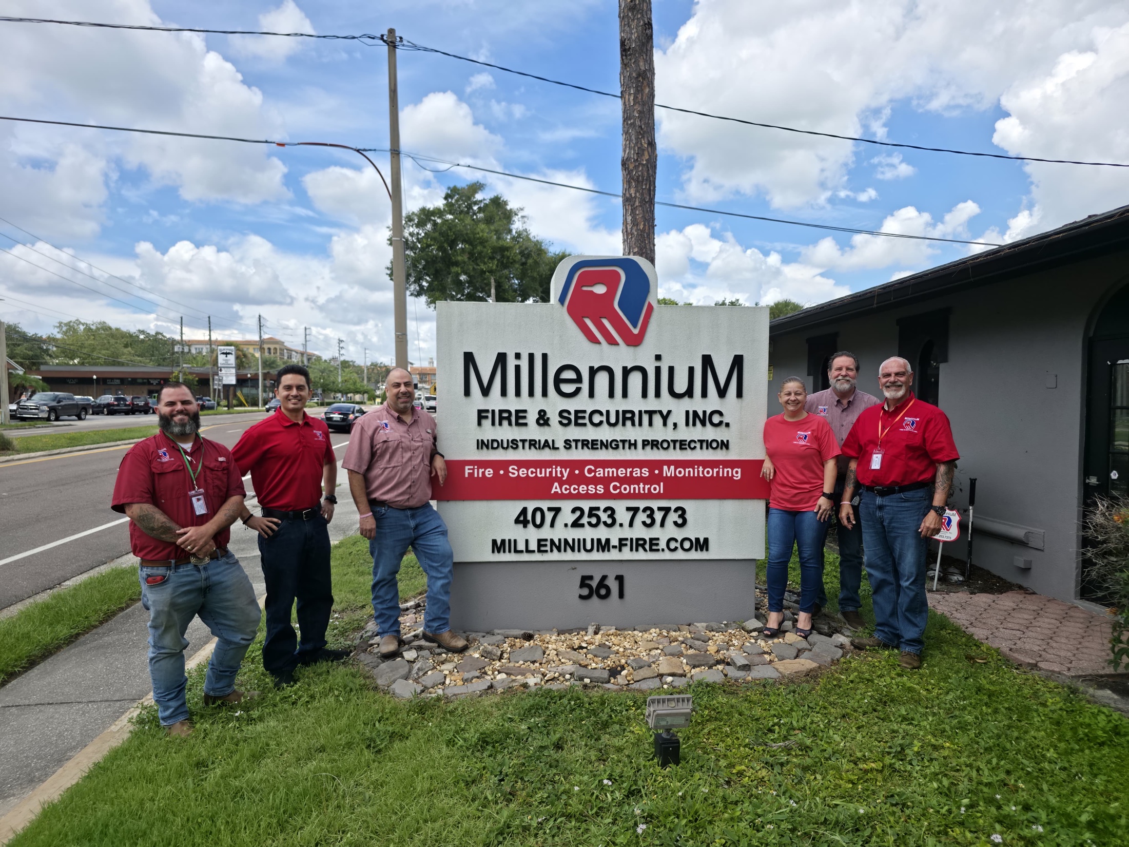 Millennium Fire & Security team standing outside the Maitland office beside the company sign